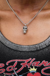 Collana in argento con pendente a forma di teschio. Il pendente è dettagliato con una finitura lucida ed è attaccato a una catena rotonda e testurizzata.