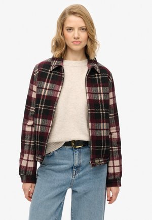 Veste en flanelle avec un motif plaid noir, bordeaux et crème, fabriquée en matériau doux, dotée d'un col et d'une fermeture zippée à la taille.