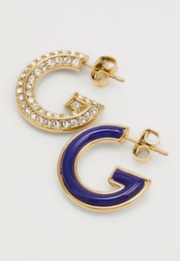Gold-tone earrings featuring a 'G' shape; one with clear rhinestones, the other with a glossy blue enamel finish.