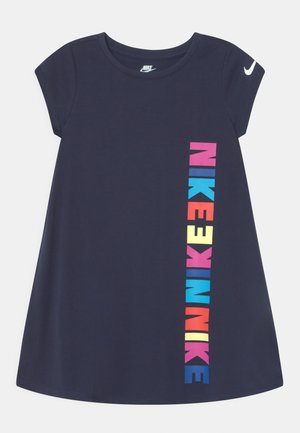 Robe Nike à manches courtes bleu marine avec un texte vertical "NIKE" coloré sur le devant et le logo swoosh blanc de Nike sur la manche gauche.