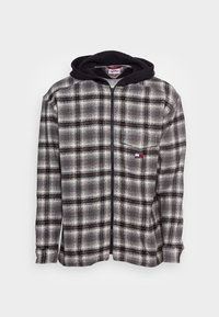 Grijze en zwarte geruite fleece jas met ritssluiting en een zwarte capuchon. Heeft een voorvak en een logo met rode accenten. Zachte textuur.