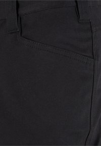 Pantaloni in tessuto elasticizzato nero con vestibilità slim. Presentano una tasca laterale e dettagli di cucitura distintivi lungo la cintura e le tasche.