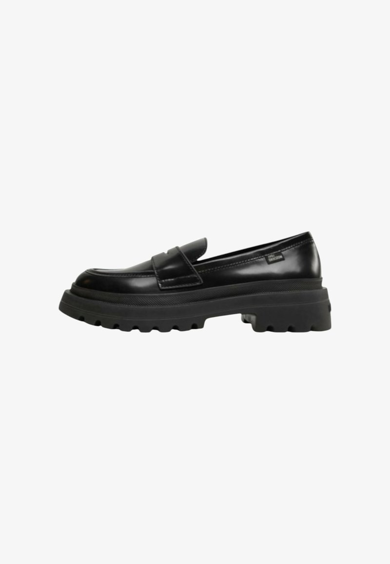 Mocassin en cuir noir avec semelle épaisse crantée, bout arrondi et bride sur le dessus, présenté de côté sur fond blanc.