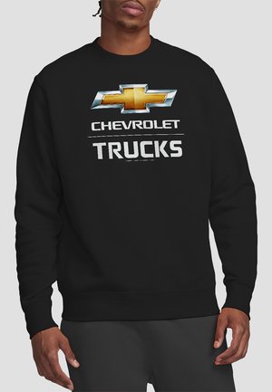 Schwarzer Pullover mit einem großen Chevrolet-Logo in Silber und Gold, darunter in fettem Weiß der Schriftzug "CHEVROLET" und "TRUCKS".