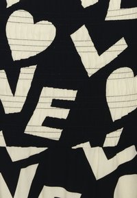 Tessuto nero con grandi lettere bianche irregolari e forme a cuore sparse casualmente su di esso.