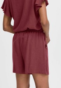 Shorts décontractés bordeaux avec taille élastique, texture douce et poches latérales, associés à un haut ample assorti avec des manches à volants.