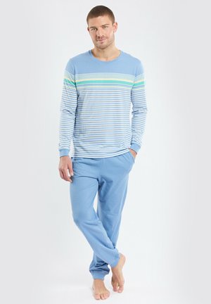 Chemise à manches longues rayée bleu et blanc associée à un pantalon de survêtement bleu uni. La chemise présente des rayures horizontales et un design à col rond.