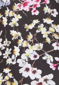 Černá látka s květinovým vzorem, obsahující bílé a růžové květy, zelené detaily a hnědé větve, s hladkým povrchem.