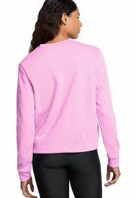Sweatshirt rose avec un col rond, des manches longues et des poignets côtelés, associé à des leggings noirs. Tissu doux avec une texture lisse.