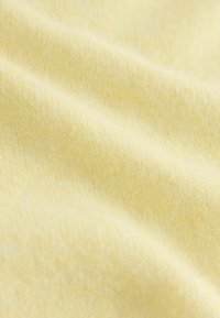 Měkká žlutá pletenina s jemnou texturou, která obsahuje jemné barevné variace a hladký povrch, ideální pro oděvy nebo doplňky.