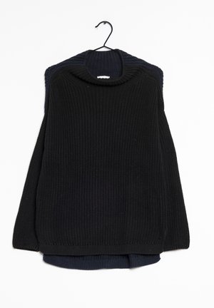 Maglione nero a maglia con texture a coste e collo ampio, appeso a un gancio nero, sovrapposto a un maglione blu navy scuro sottostante.