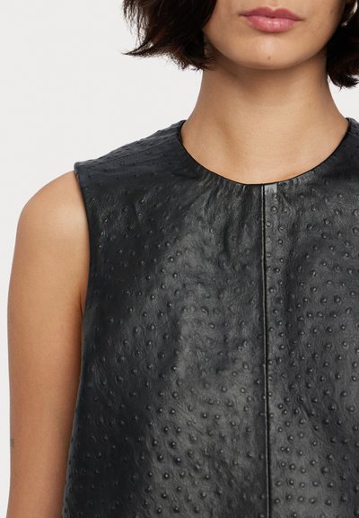 Black sleeveless top made of textured leather with a smooth finish. Features a round neck and visible stitching down the center.