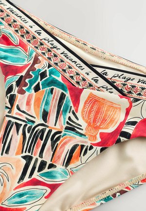 Színes bikini alsó absztrakt virág- és geometriai mintákkal, derékpántján "vacances à la plage" felirattal és apró virágmotívumokkal.