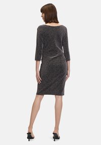 Abito in maglia a tre quarti, colore grigio scuro con filo metallico, design aderente, lunghezza al ginocchio e dettagli delle cuciture ridotti al minimo.