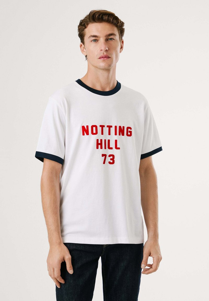 Λευκό βαμβακερό t-shirt με κόκκινο κείμενο "NOTTING HILL 73". Διαθέτει ναυτικό μπλε ριγέ περιλαίμιο και στρώσεις μανικιών. Κλασική εφαρμογή, κοντά μανίκια.