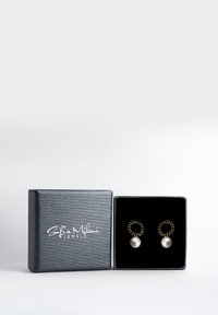 Guldtonade örhängen med en cirkulär design och texturerade detaljer, samt en stor, glänsande vit pärla. Presenteras i en svart texturerad låda.