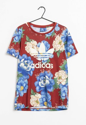 Koszulka Adidas z krótkim rękawem na czerwonym tle, z dużym niebiesko-białym kwiatowym nadrukiem i białym logo trefoil na środku przodu.