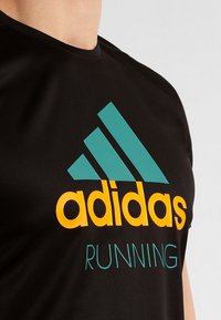 Black short-sleeve sports shirt with a textured fabric. Features a teal Adidas logo and orange "RUNNING" text on the front.