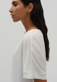 T-shirt blanc à manches courtes, avec une texture lisse, une coupe décontractée et un col rond, au design uni et à la coupe douce.