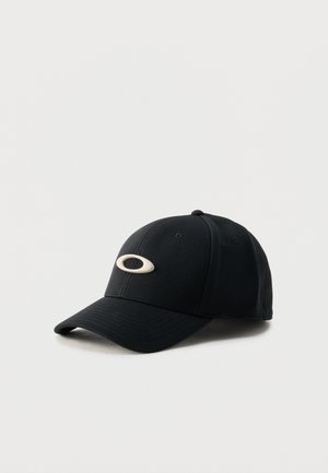 Gorra de béisbol negra con visera curva y logotipo ovalado beige centrado en el panel frontal, mostrada sobre un fondo claro y liso.
