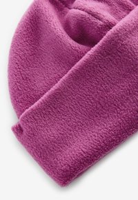 Beanie in pile di un vivace viola, con una texture morbida e un design con risvolto. Il tessuto appare caldo e leggermente peloso.