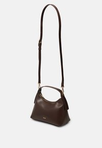 Τσάντα χειρός σκούρου καφέ δέρματος με χρυστό φερμουάρ, κοντή λαβή και μακρύ ρυθμιζόμενο ιμάντα ώμου πάνω σε απλό ανοιχτό φόντο.