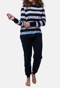 Långärmad randig topp i marinblått, ljusblått och vitt, ihopparad med marinblå joggerbyxor. Bekväm tyg med ribbade muddlinningar och vrister.