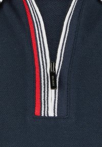 Polo shirt marine avec un design à quart de fermeture éclair. Présente un col côtelé avec des rayures blanches et rouges. Texture en tricot doux ; détail du tirette de fermeture éclair métallique.