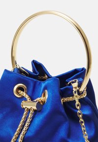 Borsa in raso blu royal con manico circolare dorato, dettagli con catena e grommet. La chiusura a coulisse ne esalta la forma e la texture.