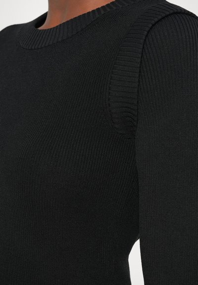 Sweater preto canelado com um decote arredondado e detalhes texturizados nos ombros, apresentando um ajuste justo e um tecido suave.