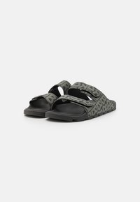 Sandales à glissière noires et grises avec des sangles à motifs, dotées de fermetures réglables, d'une semelle intérieure texturée et d'une semelle extérieure en caoutchouc durable.