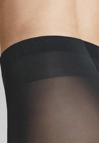 Black sheer tights with a textured waistband, featuring a smooth finish. The fabric is lightweight and semi-transparent, showcasing skin tone.