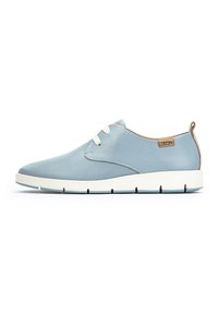 Zapatilla azul clara con un exterior de malla y cuero suave, que presenta cordones blancos, una punta redondeada y una suela plana blanca.