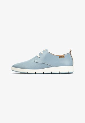 Lichtblauwe sneaker met een mesh- en gladleren buitenkant, voorzien van witte veters, een ronde neus en een vlakke witte zool.