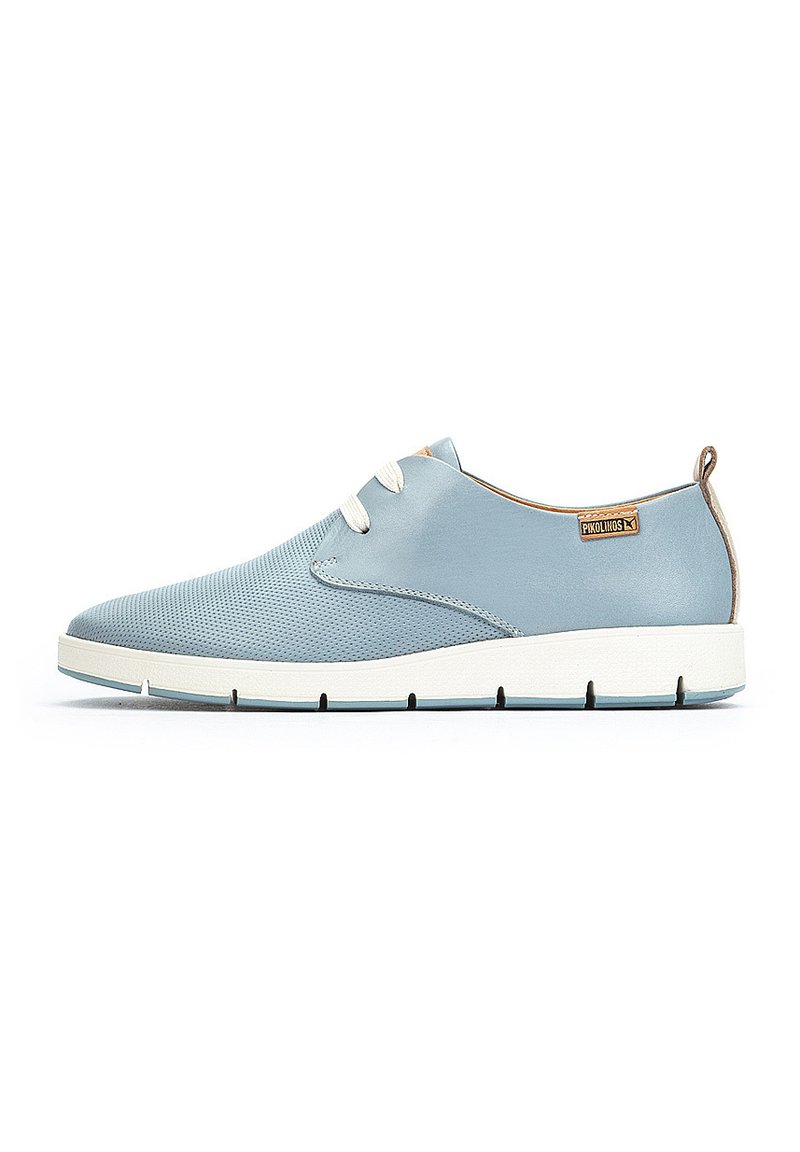 Zapatilla azul clara con un exterior de malla y cuero suave, que presenta cordones blancos, una punta redondeada y una suela plana blanca.