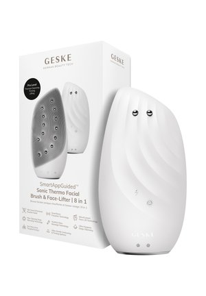 Hvid buet sonisk termo ansigtsbørste og ansigtsløfterenhed med to metalkugler, vist ved siden af sin emballage.