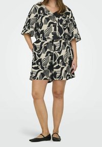 Beige Set aus Kurzarm-V-Ausschnitt-Oberteil und Shorts mit schwarzen abstrakten Mustern. Leichter Stoff, elastischer Bund und seitliche Taschen.