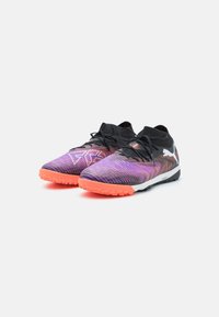 Chaussures de sport multicolores arborant un design rayé noir et rose, une tige texturée, des lacets noirs et des semelles orange vif.