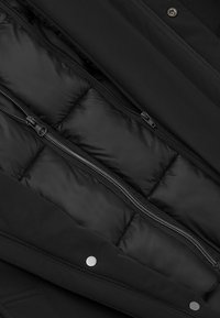 Czarna ocieplana kurtka od wewnątrz z pikowanymi sekcjami, wyposażona w centralny zamek błyskawiczny i zatrzaski; gładka tekstura materiału.