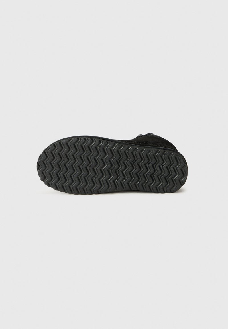Semelle noire de chaussure avec un motif de crampons en zigzag. Fabriquée en caoutchouc avec une surface texturée, dotée d'une conception à bout rond et d'une fermeture à glissière sur le côté.