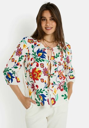 Blouse légère imprimée florale avec des manches trois-quarts, un col rond et un détail à nouer à l'avant. Les couleurs incluent le rouge, le bleu, le vert et le jaune.
