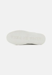 Podeszwa białego sneakeru z fakturowanym bieżnikiem i widoczną na spodzie wytłoczoną nazwą marki "ALMA EN PENA".