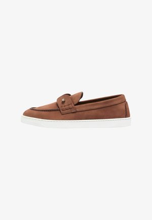 Mocasín marrón de cuero tipo slip-on con suela blanca de goma y un pequeño detalle metálico en la correa superior, mostrado de lado.