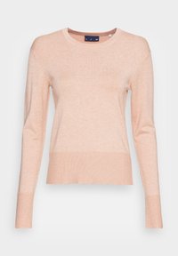 Pull en maille pêche avec un col rond, manches longues et ourlets côtelés. Texture douce avec une silhouette légèrement ample.