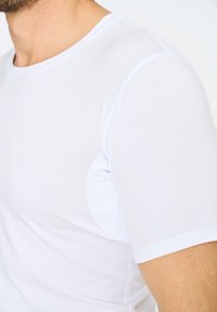 Hvid kortærmet t-shirt lavet af letvægtsstof, med rund halsudskæring og glat tekstur samt minimal syning på kanterne.