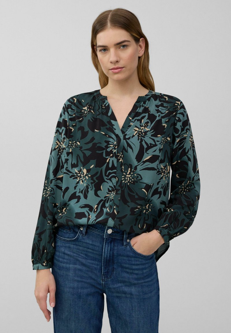 Blumenbluse in grün, schwarz und creme mit entspannter Passform, V-Ausschnitt und langen Ärmeln. Glattes Material mit einem auffälligen Blumenmuster.