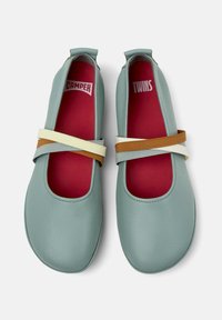 Bailarinas de cuero verde azulado con correas elásticas coloridas; el interior es rojo; cuentan con punta redondeada y un diseño minimalista.
