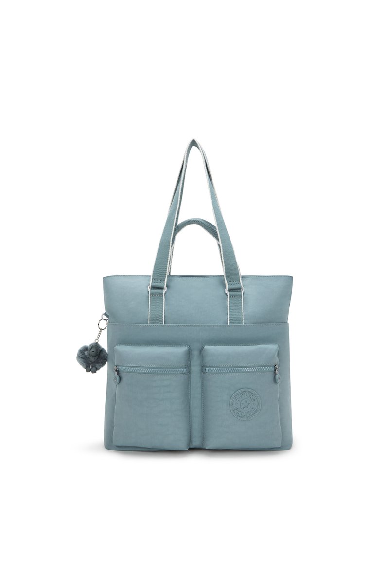 Hellblaues Tote-Bag mit zwei vorderen Reißverschlusstaschen, einem strukturierten Material, Schulterriemen und einem flauschigen Pompon-Accessoire. Mit Logo-Patch.