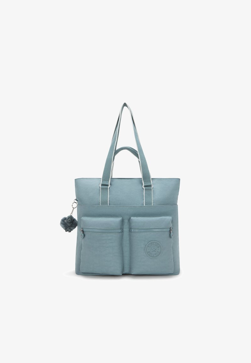 Ljusblå tote bag med två framfickor med dragkedja, en texturerad yta, axelremmar och en fluffig pom-pom-accessoar. Har en logotypapplikation.