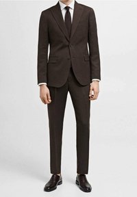 Brauner Anzug aus strukturiertem Stoff mit schlanker Passform, bestehend aus einreihigem Sakko, Revers mit Kerb, und passenden Hosen. Braune Lederschuhe.